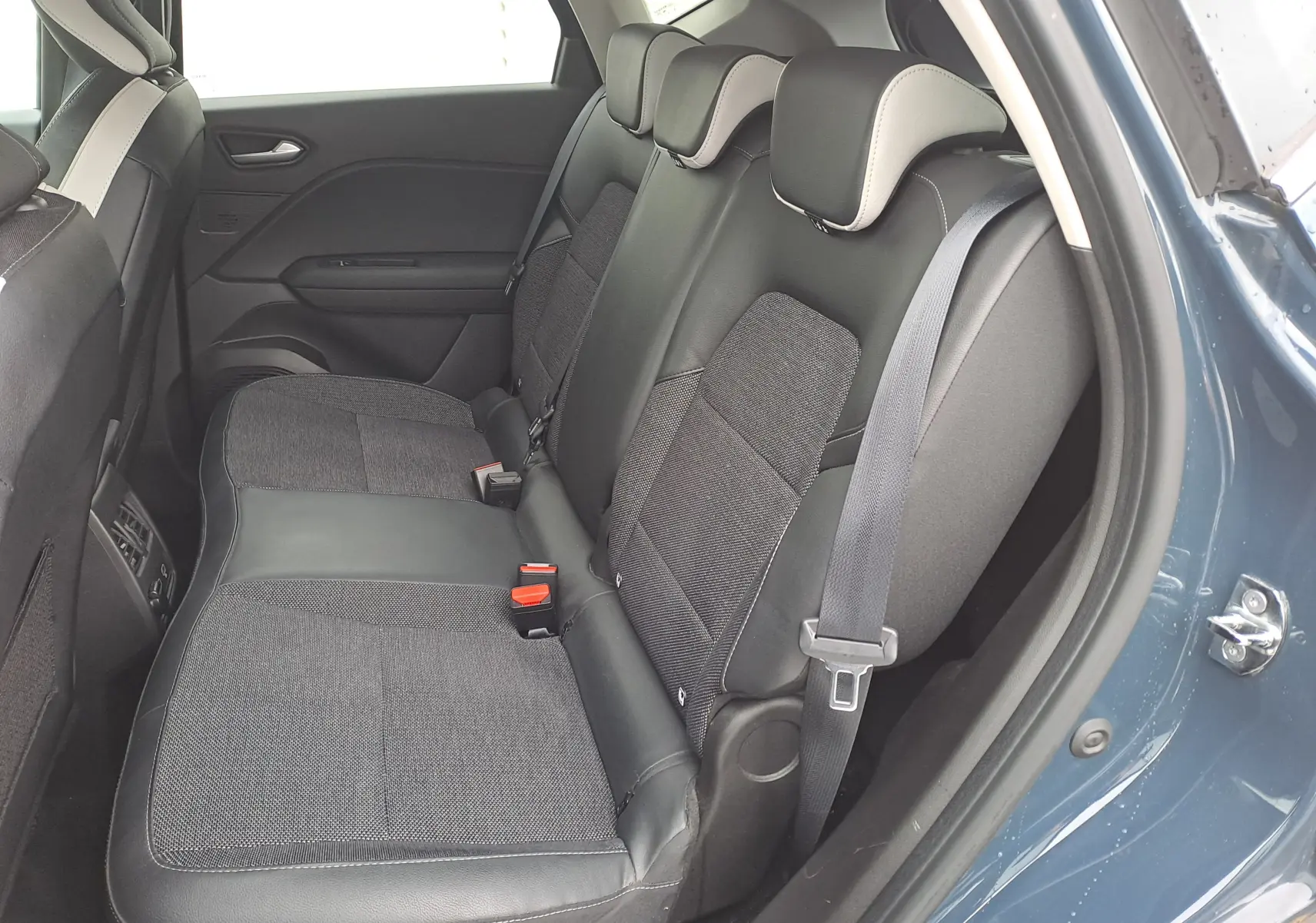 Vue intérieure côté droit des sièges arrière en tissu et cuir noir du Renault Captur bleu marine 2022, porte ouverte.