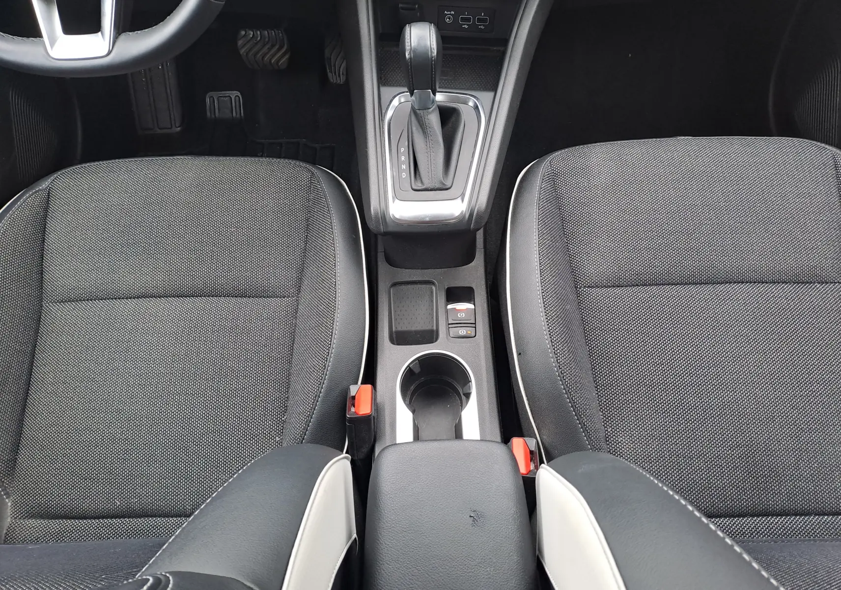 Vue intérieure centrée sur la console centrale et les sièges avant noirs avec surpiqûres blanches du Renault Captur 2022.