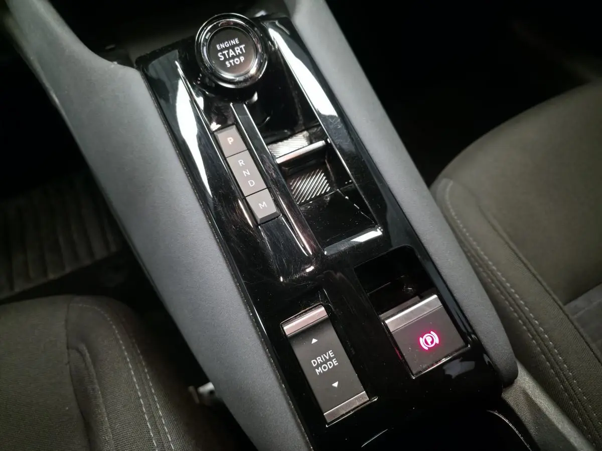 Gros plan sur la console centrale noire brillante de l'Alfa Romeo Junior 1.2 Ibrida avec sélecteur de mode de conduite et frein électrique.