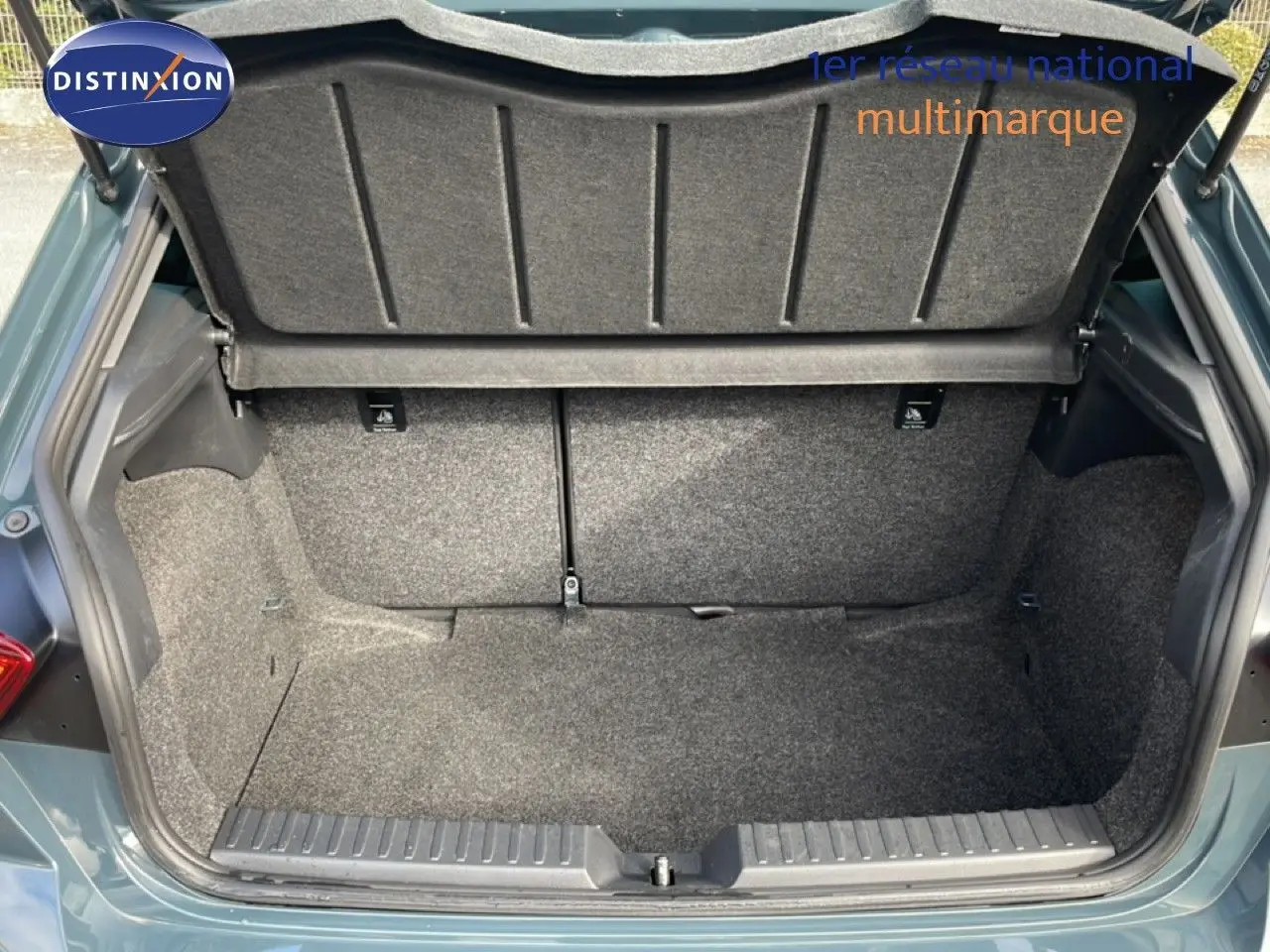 Coffre ouvert vu de l'arrière d'une SEAT Ibiza bleu Fjord, montrant l'espace de chargement vide et la moquette grise.
