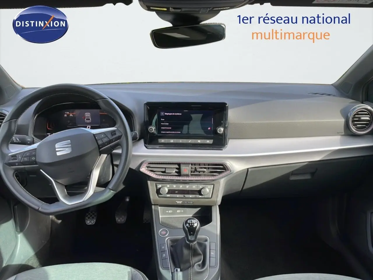 Vue intérieure du tableau de bord de la SEAT Ibiza 2025 bleu Fjord, avec volant multifonction et boîte manuelle.