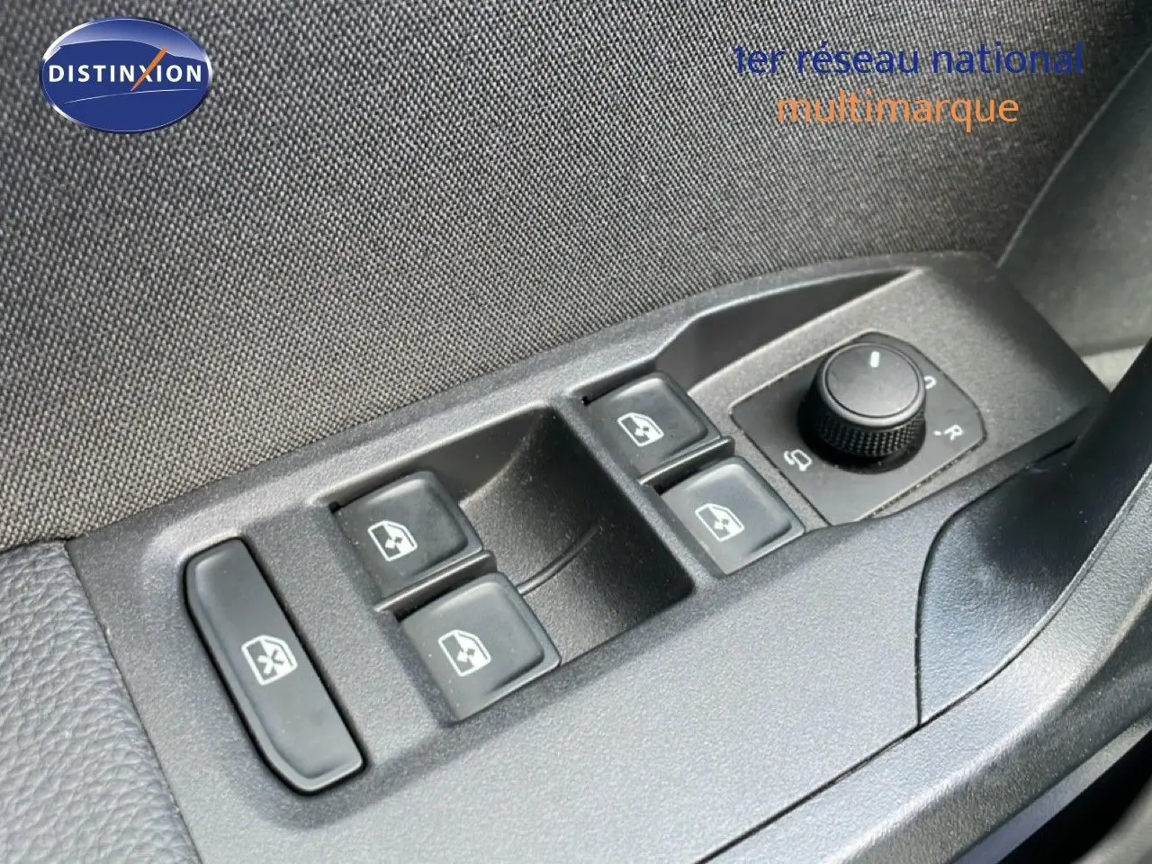 Gros plan sur les commandes des vitres électriques et réglage des rétroviseurs côté conducteur d’une SEAT Ibiza bleu Fjord.