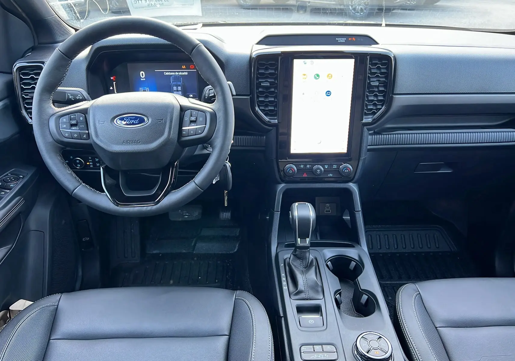 Vue intérieure frontale du Ford Ranger 2025 noir agate, montrant volant cuir multifonctions et écran tactile vertical.