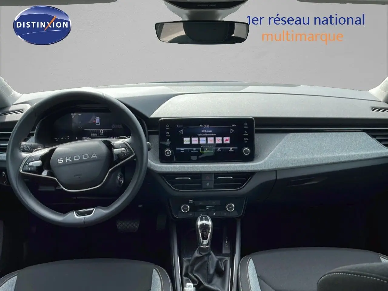 Vue intérieure frontale du tableau de bord et volant Skoda Scala 2025, finition tissu gris noir avec écran tactile central.