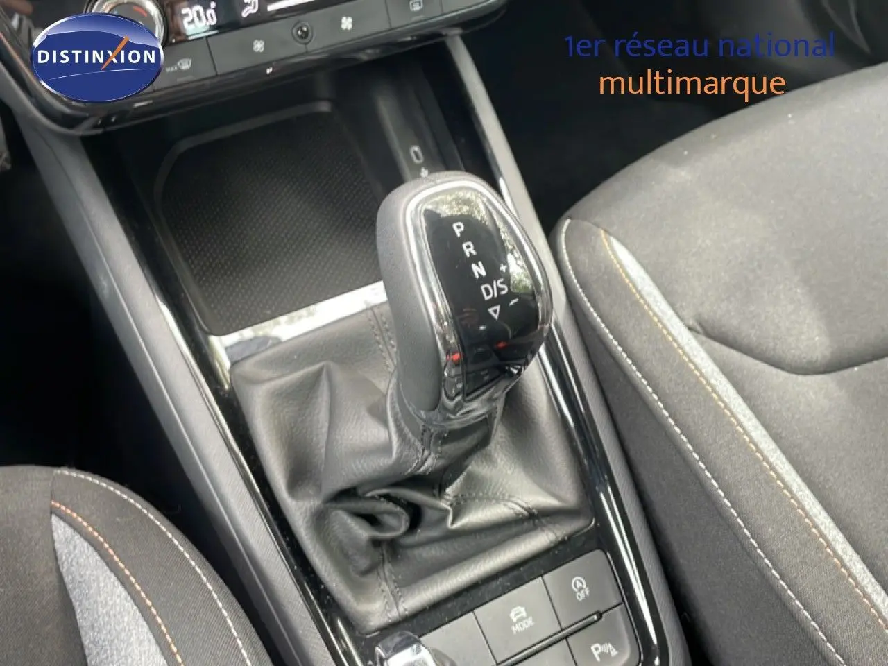 Gros plan sur la console centrale de la Skoda Scala 2025, avec levier de boîte automatique en cuir noir et siège tissu gris.
