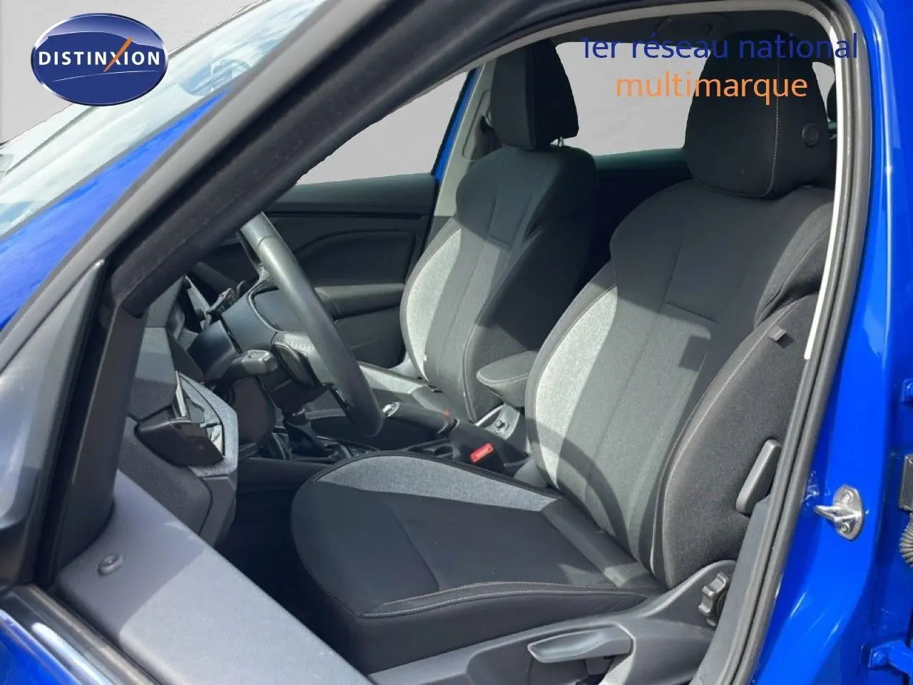 Vue intérieure côté conducteur d'une Skoda Scala 2025 bleu racing metal, sièges tissu gris et noir avec volant multifonction.