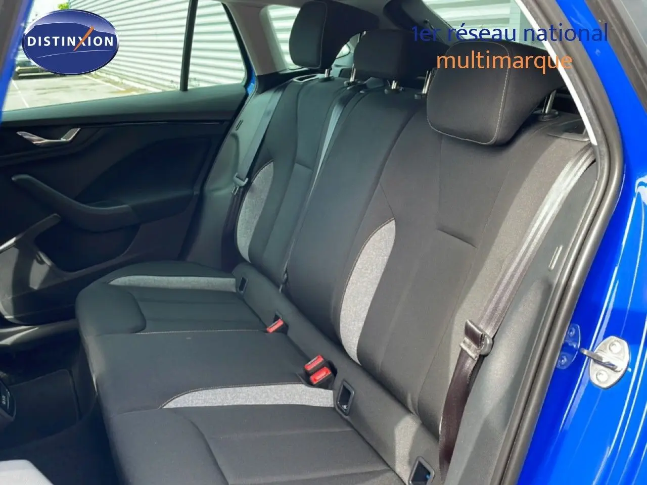 Vue côté droit de l’intérieur arrière d’une Skoda Scala bleu racing metal avec sièges tissu noir et gris clair.