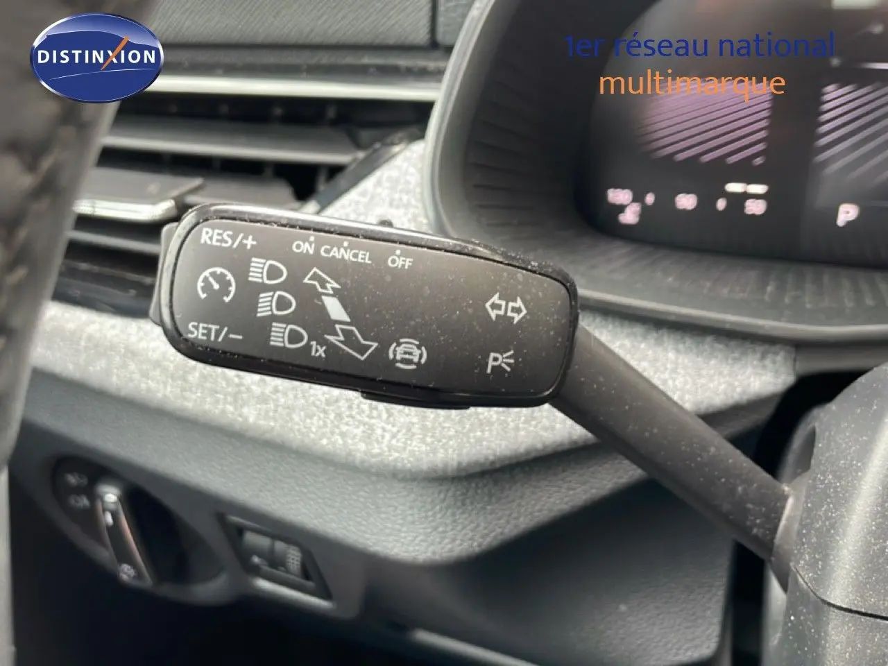 Gros plan sur la commande de régulateur de vitesse à gauche du volant dans l’habitacle gris foncé d’une Skoda Scala 2025.