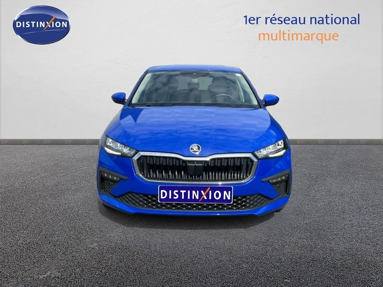 Vue avant d'une Skoda Scala 2025 bleu racing metal avec calandre noire et phares LED allumés.