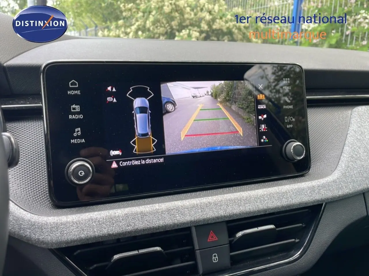 Vue rapprochée de l'écran central de la Skoda Scala bleu racing metal affichant la caméra de recul avec guidage.