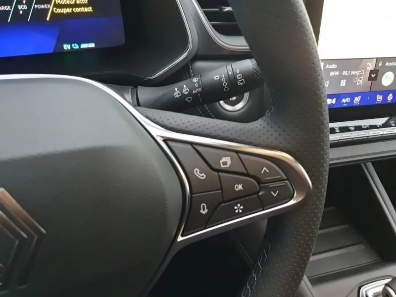Gros plan sur le volant noir étoilé du Renault Symbioz 2025, avec commandes multifonctions et écran tactile en arrière-plan.