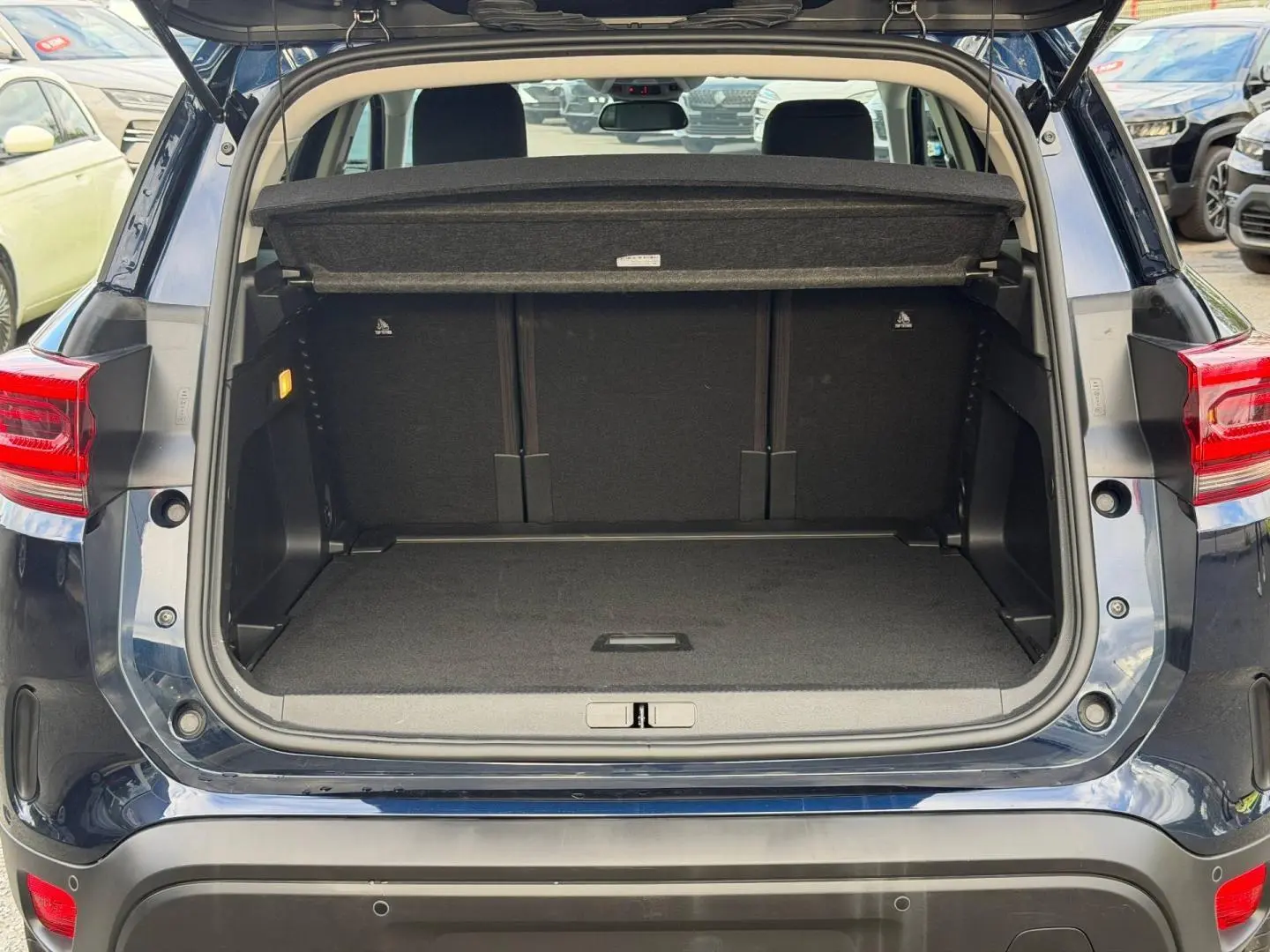 Coffre ouvert vu de l'arrière du Citroën C5 Aircross Bleu Eclipse avec cache-bagages et banquette arrière visible.
