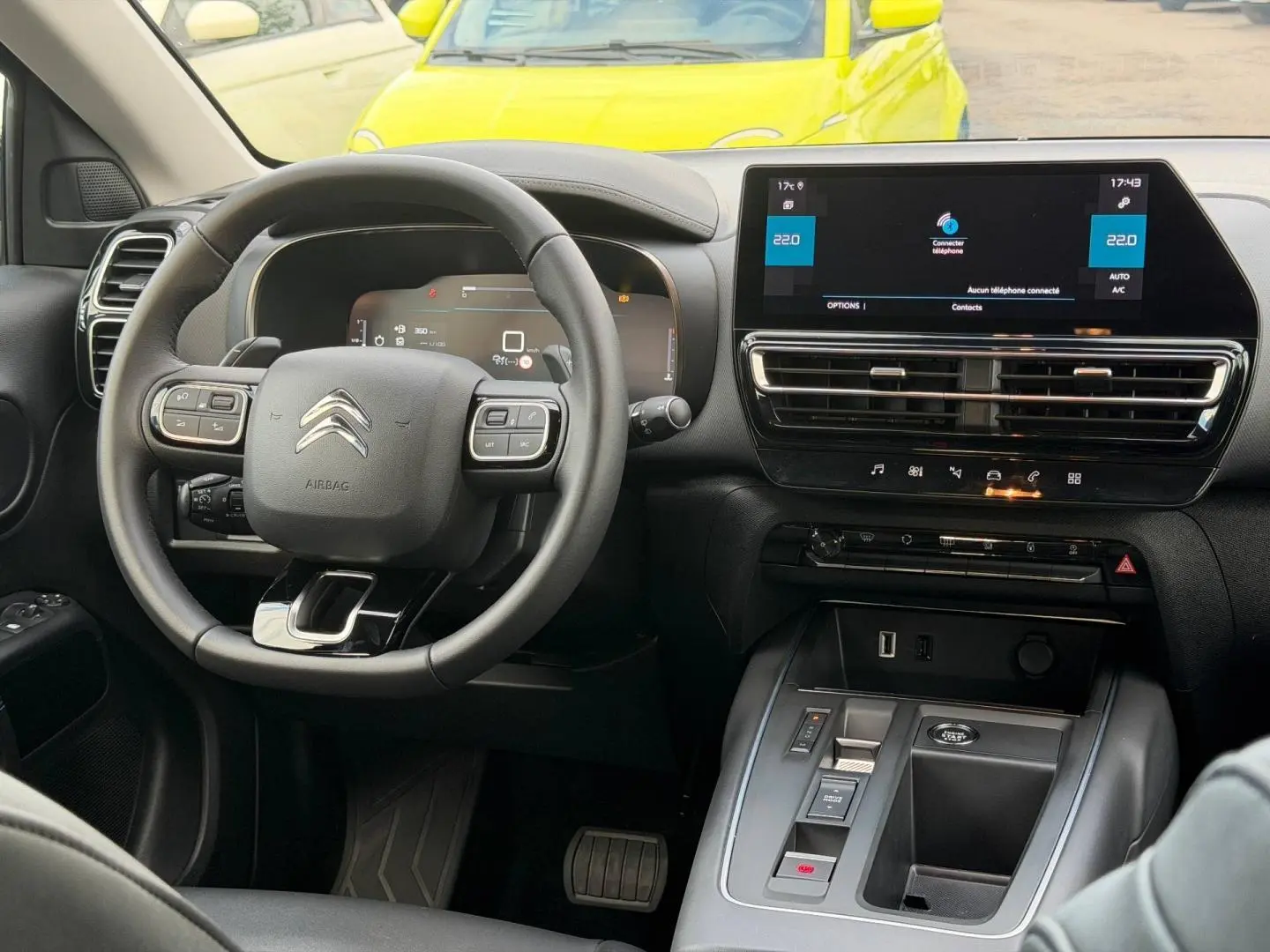 Vue intérieure du poste de conduite du Citroën C5 Aircross 2025, volant cuir et écran tactile central noir.