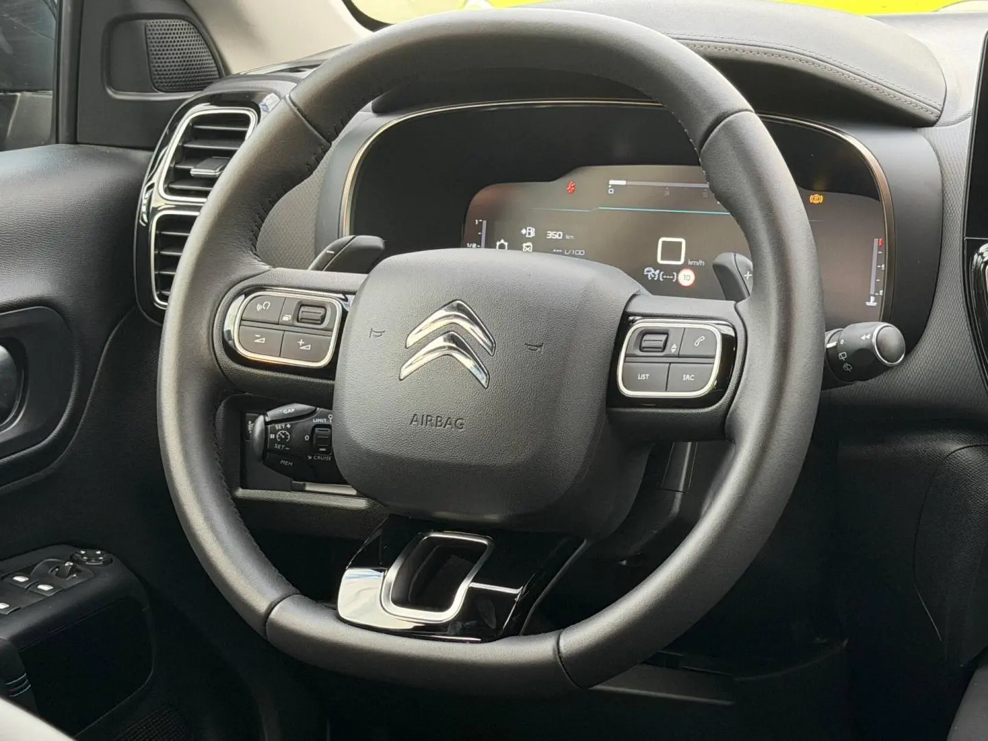 Vue rapprochée du volant cuir multifonction noir du Citroën C5 Aircross 2025 avec tableau de bord numérique.