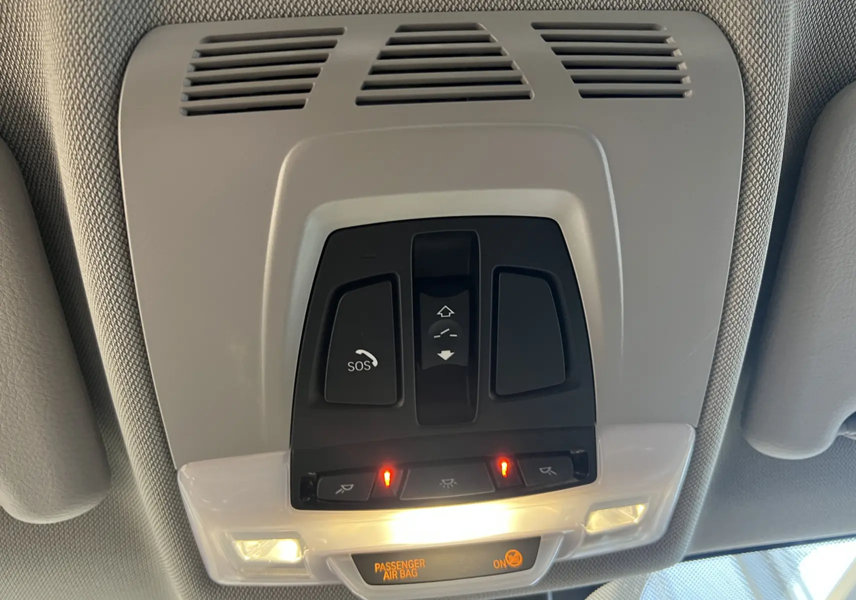 Panneau de commandes au plafond avec éclairage et bouton SOS dans l'habitacle du BMW X1 F48 noir, version Lounge 2017.