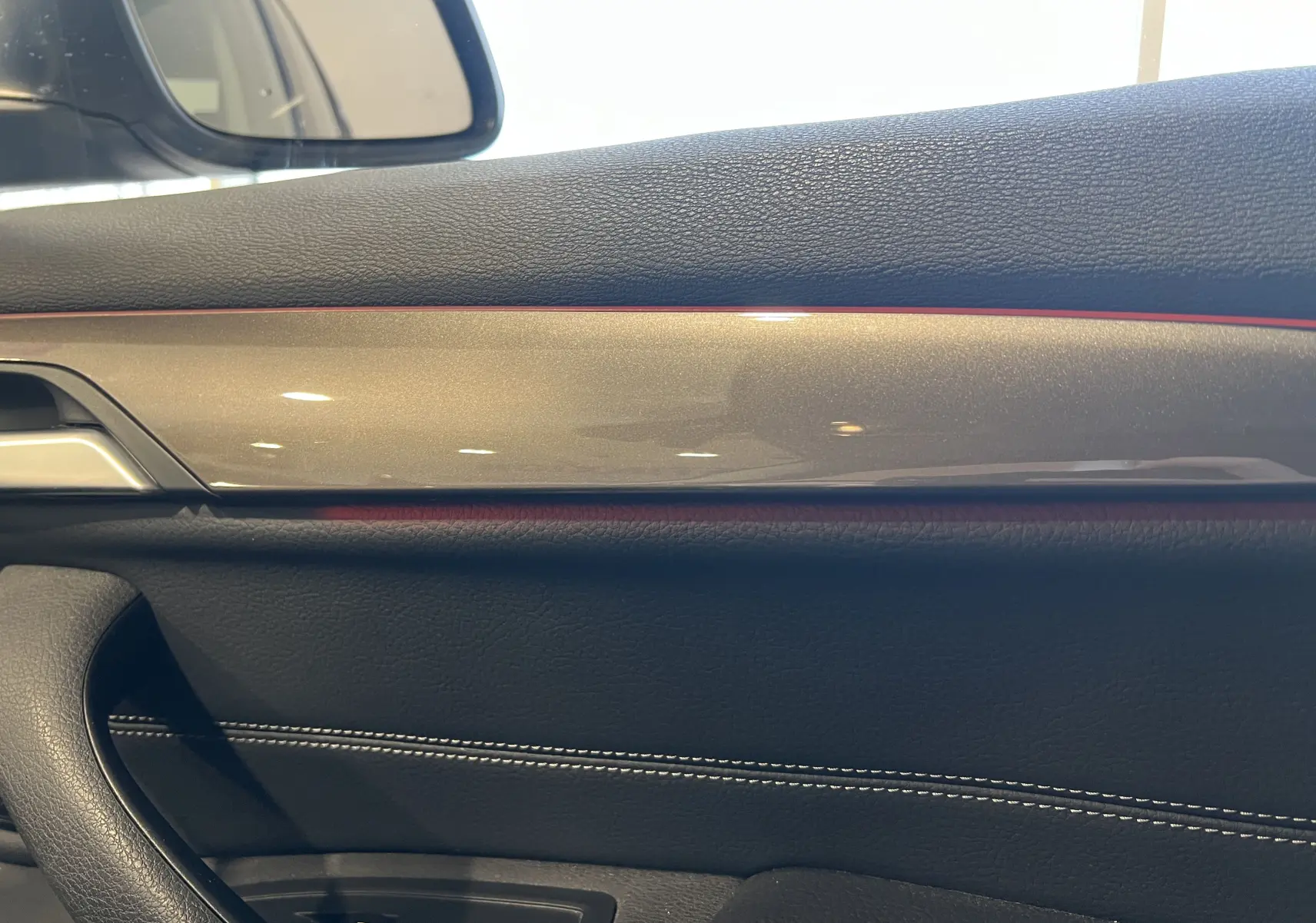 Détail de la garniture intérieure côté gauche avec surpiqûres blanches et insert décoratif brillant du BMW X1 F48 noir 2017.