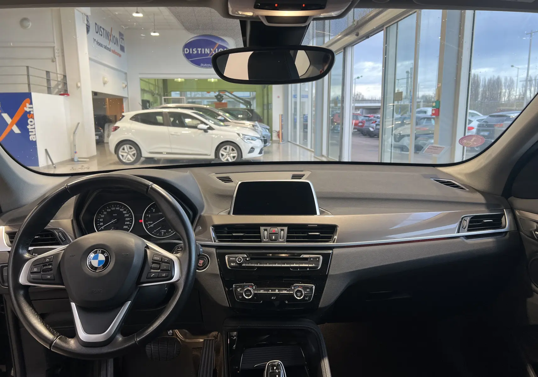 Vue intérieure avant du BMW X1 F48 noir 2017, tableau de bord moderne avec écran central et volant multifonction.