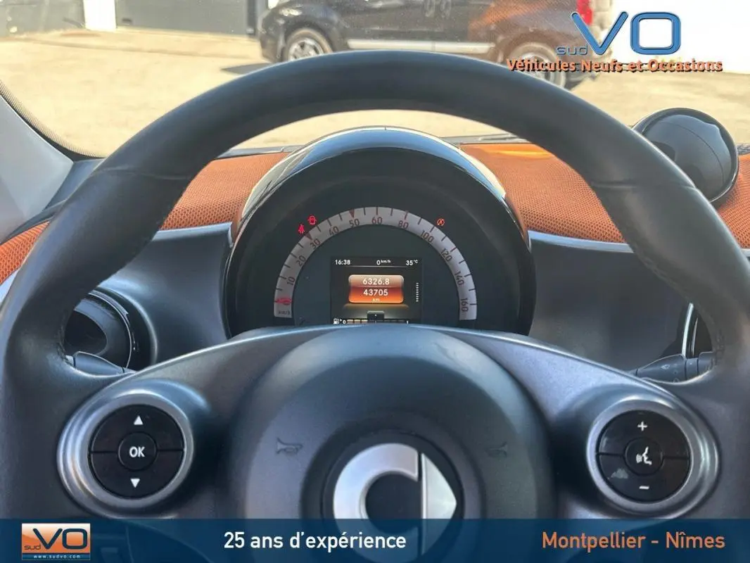 Vue depuis le volant d'une Smart Forfour noire de 2015, affichage numérique du compteur au centre du tableau de bord.