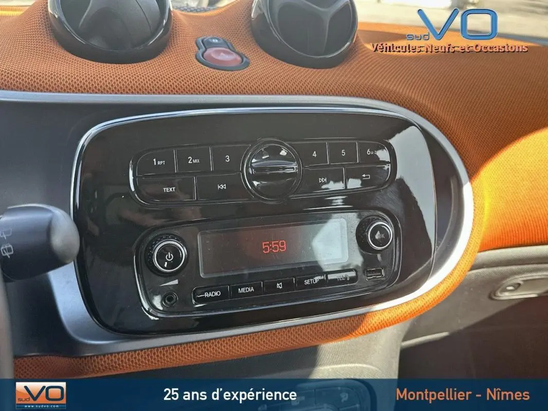 Tableau de bord orange et noir de la Smart Forfour 2015, avec commandes radio et affichage digital à 5:59.