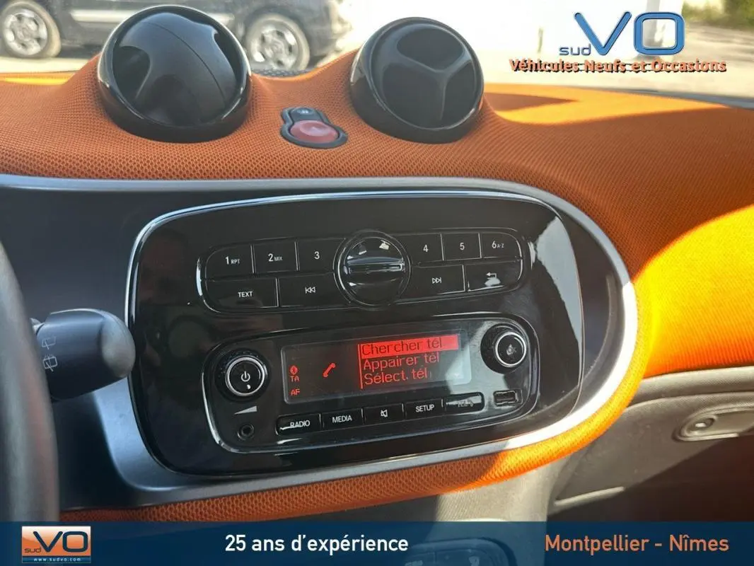 Tableau de bord orange vif de la Smart Forfour 2015 avec console centrale noire et commandes radio visibles.