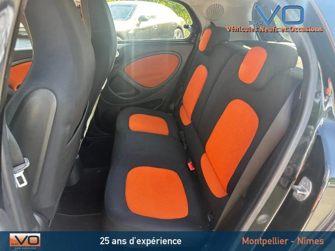 Vue intérieure arrière droite de la Smart Forfour noire 2015 avec sièges noirs et orange et panneaux de porte assortis.