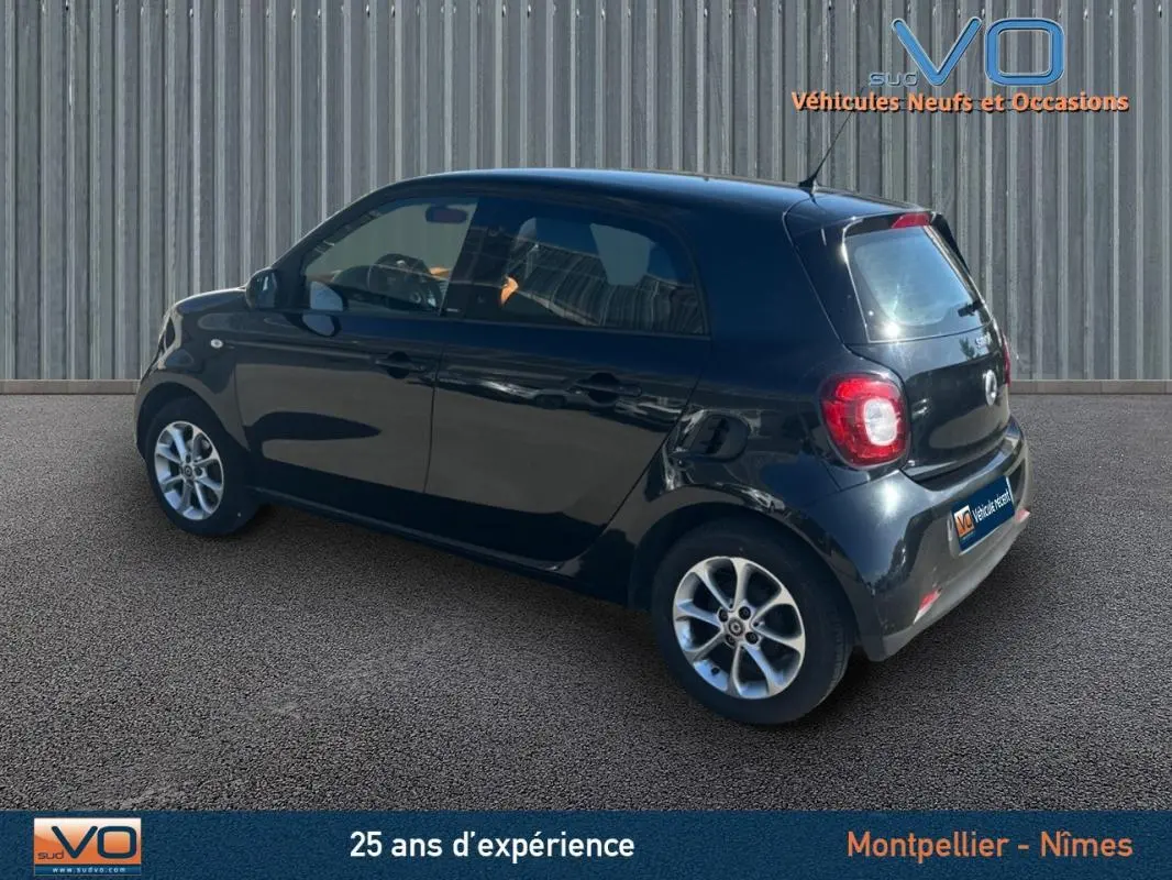 Vue 3/4 arrière droite d'une Smart Forfour noire de 2015, compacte avec feux arrière arrondis et jantes argentées.