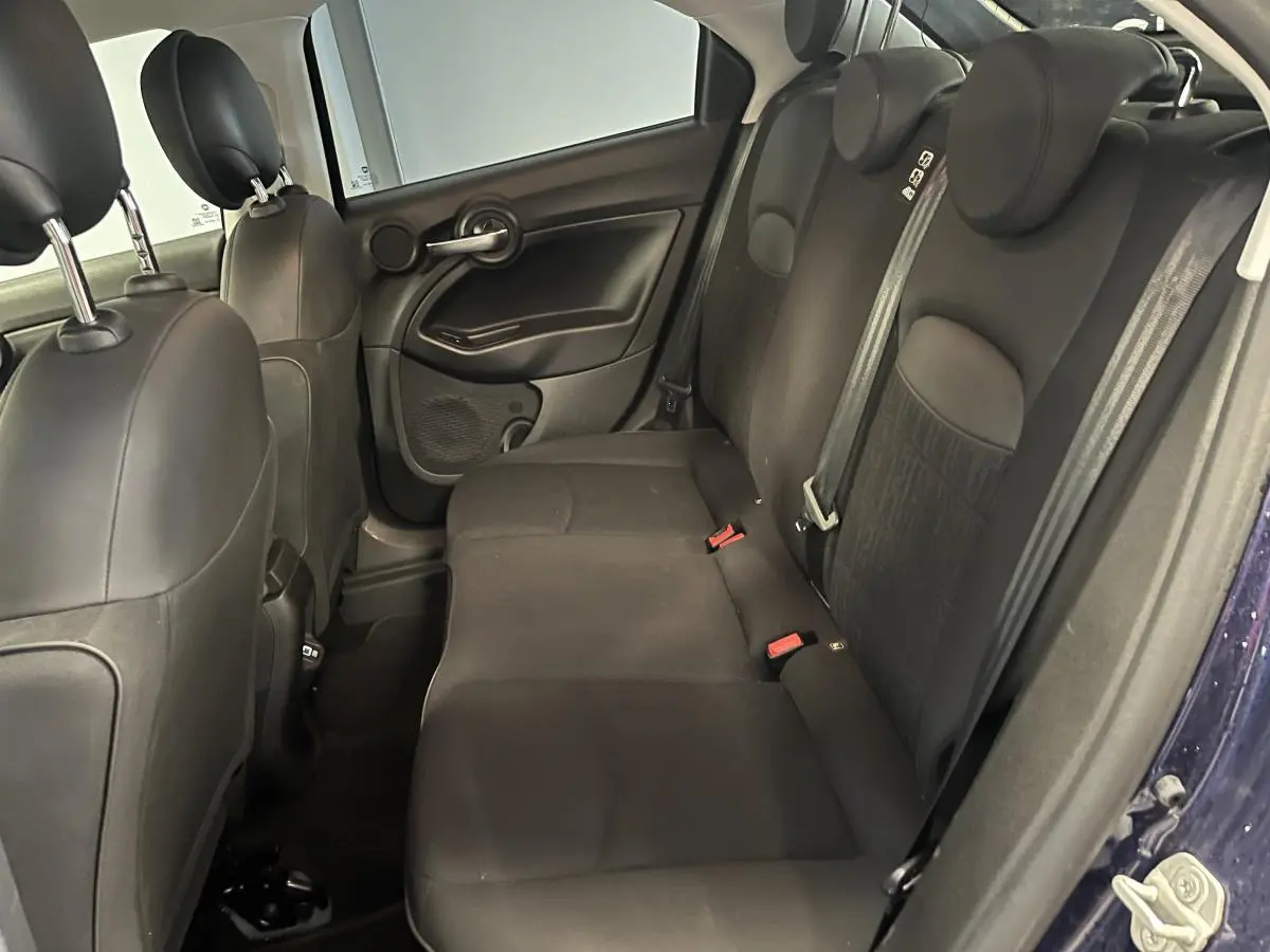 Vue latérale gauche de l'habitacle arrière noir de la Fiat 500X 2024 avec sièges tissu et appuie-tête intégrés.
