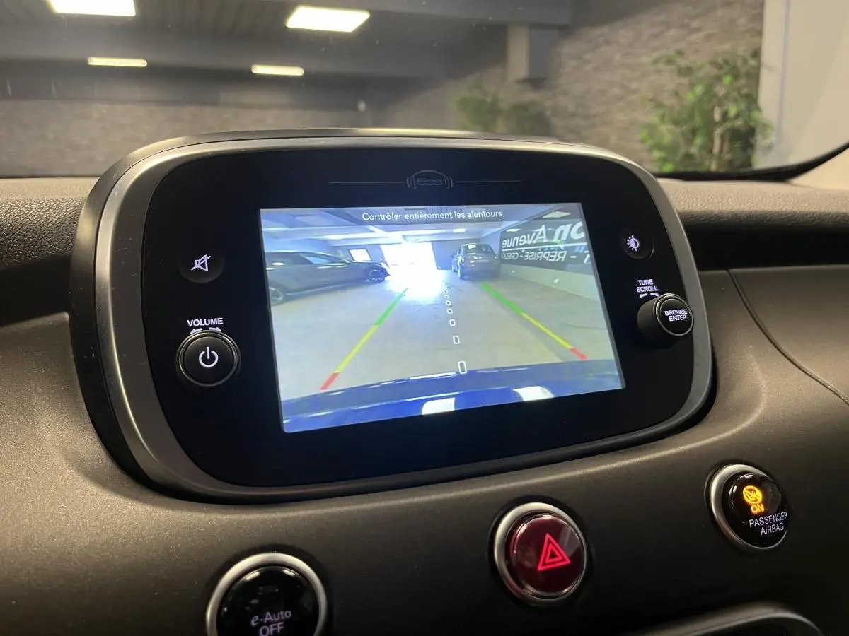 Écran central de la Fiat 500X bleu montrant la caméra de recul avec guidage de trajectoire en intérieur.
