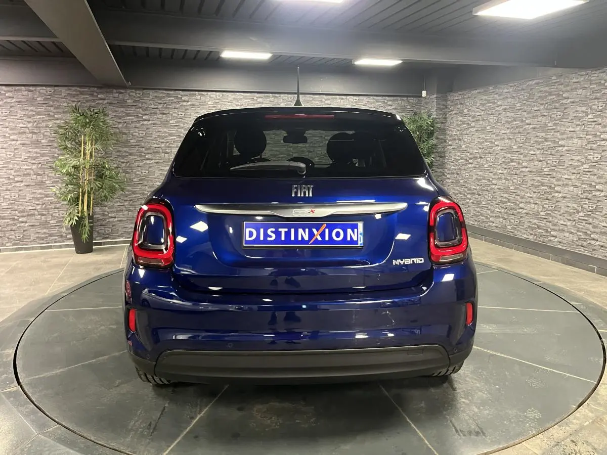 Vue arrière d'une Fiat 500X bleu métallisé avec feux LED et logo Hybrid dans un showroom.