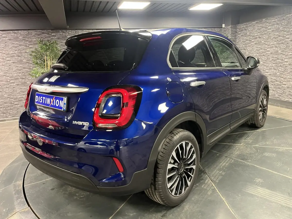 Fiat 500X bleu métallisé vue 3/4 arrière droit, avec jantes alliage 17'' et vitres surteintées.