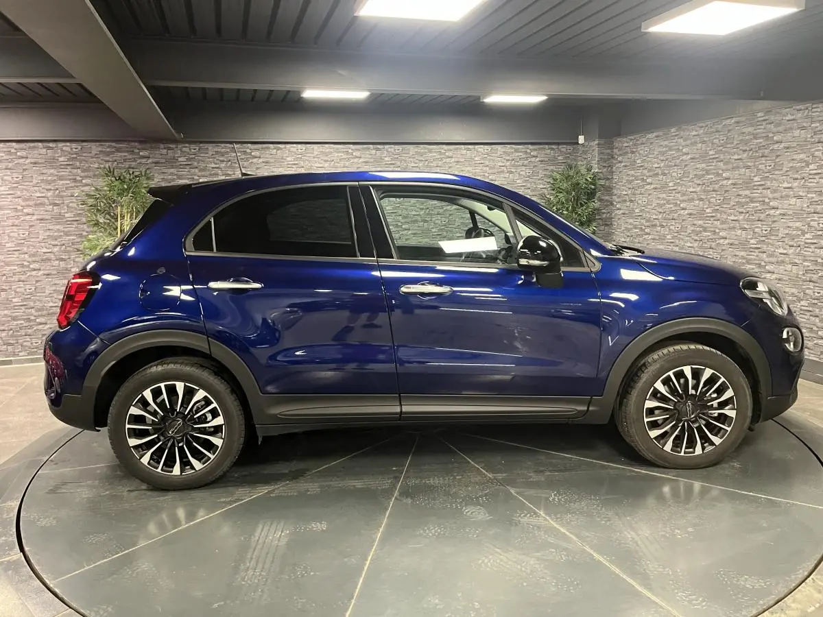 Profil côté gauche du Fiat 500X bleu métallisé 2024 avec jantes alliage 17 pouces et vitres surteintées.
