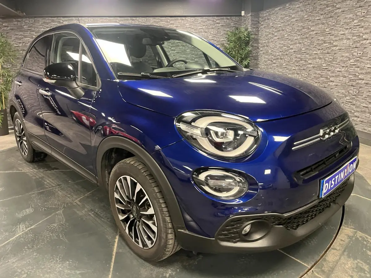 Fiat 500X bleu métallisé vue 3/4 avant droit avec jantes alliage 17'' et projecteurs LED distinctifs.