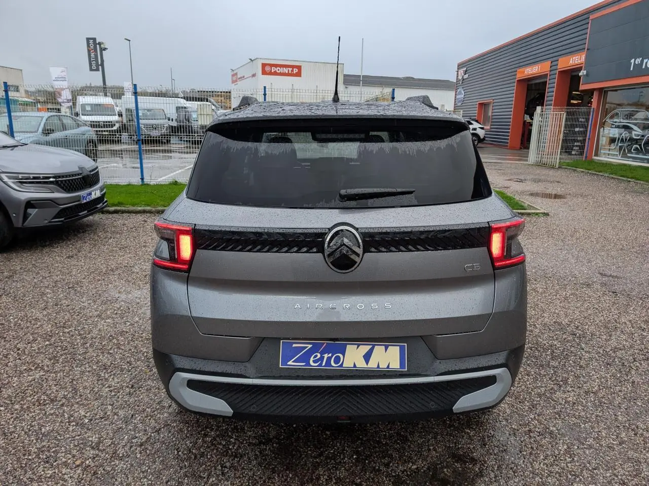 Vue arrière d'un Citroën C3 Aircross gris métallisé avec toit noir et feux arrière LED allumés.