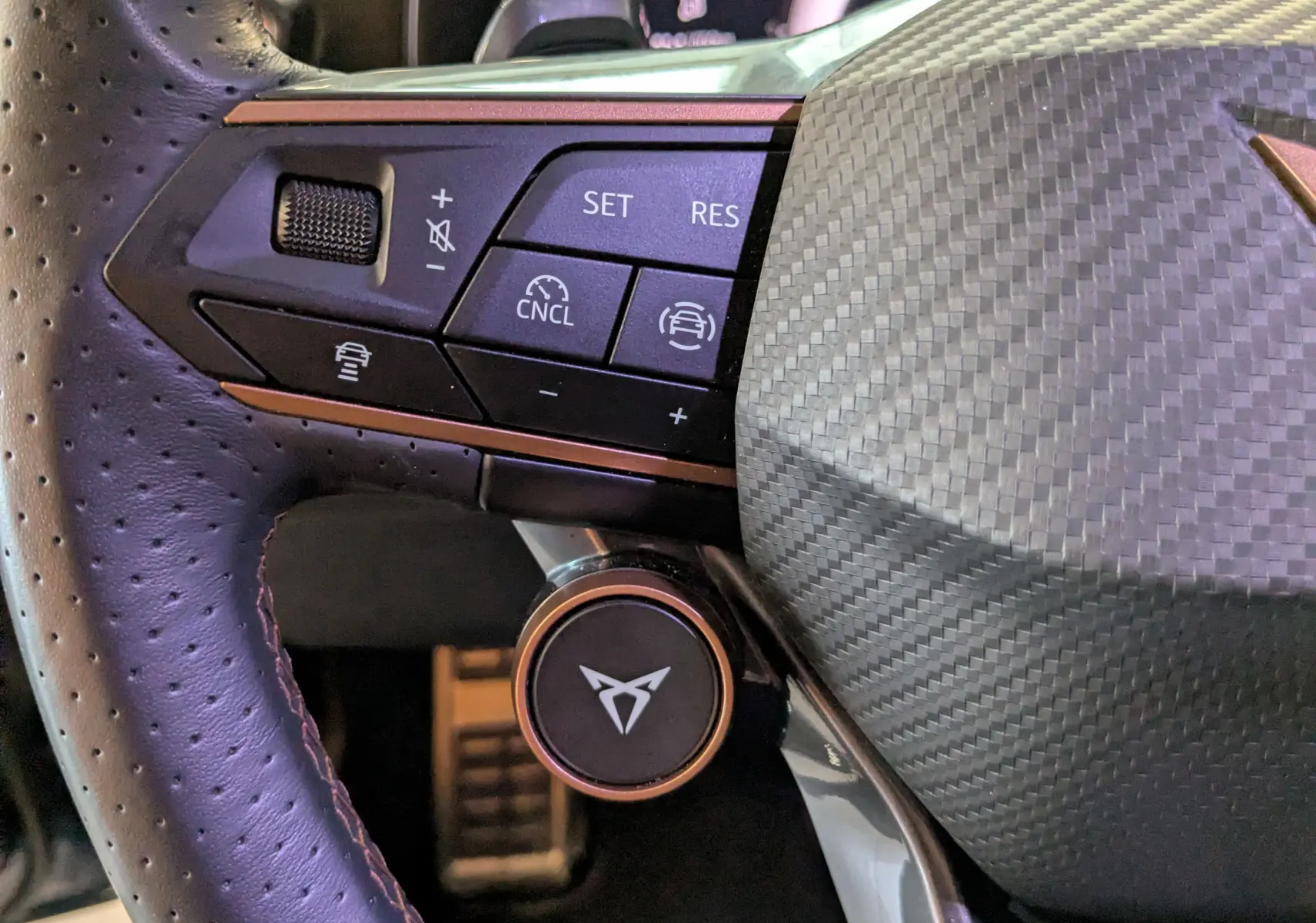 Gros plan sur le volant cuir perforé du CUPRA LEON ST 2025 avec commandes multifonctions et insert carbone.