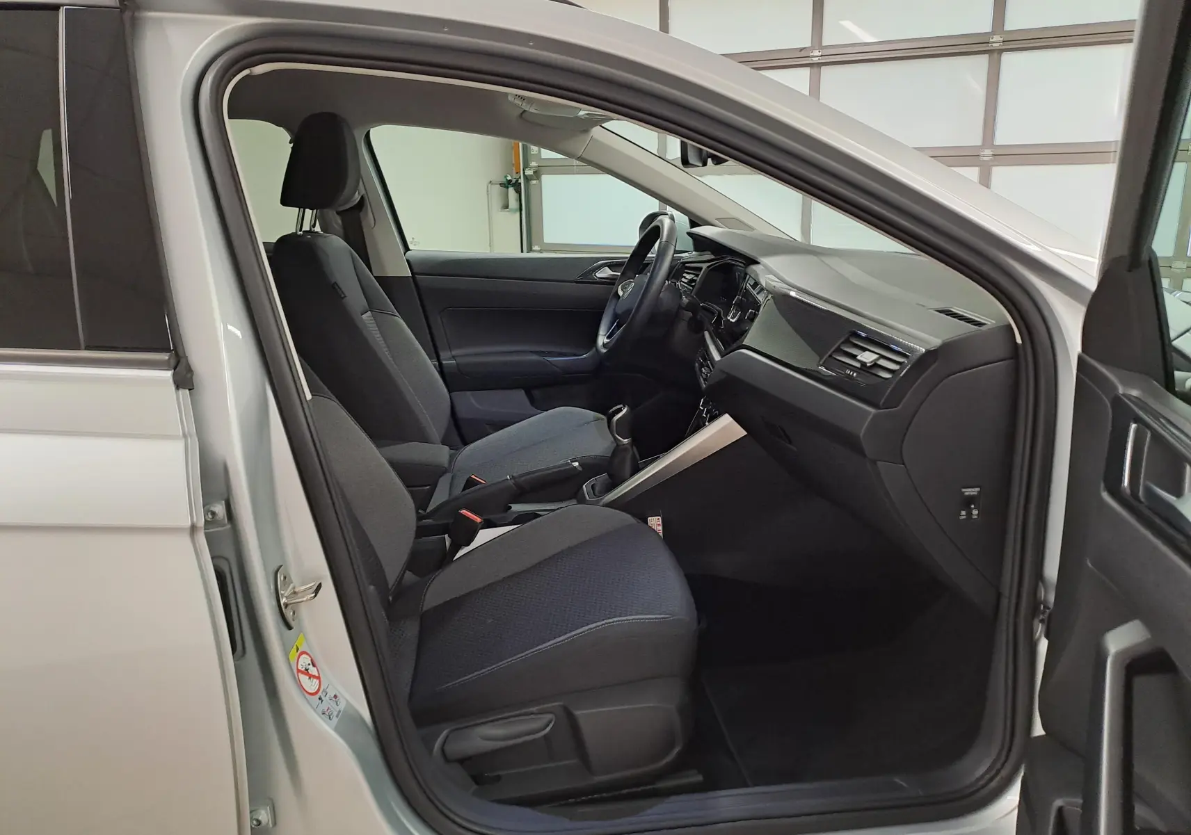 Intérieur du Volkswagen Taigo 2025 en Reflet d'argent, vue côté gauche avec sièges noirs et tableau de bord moderne.