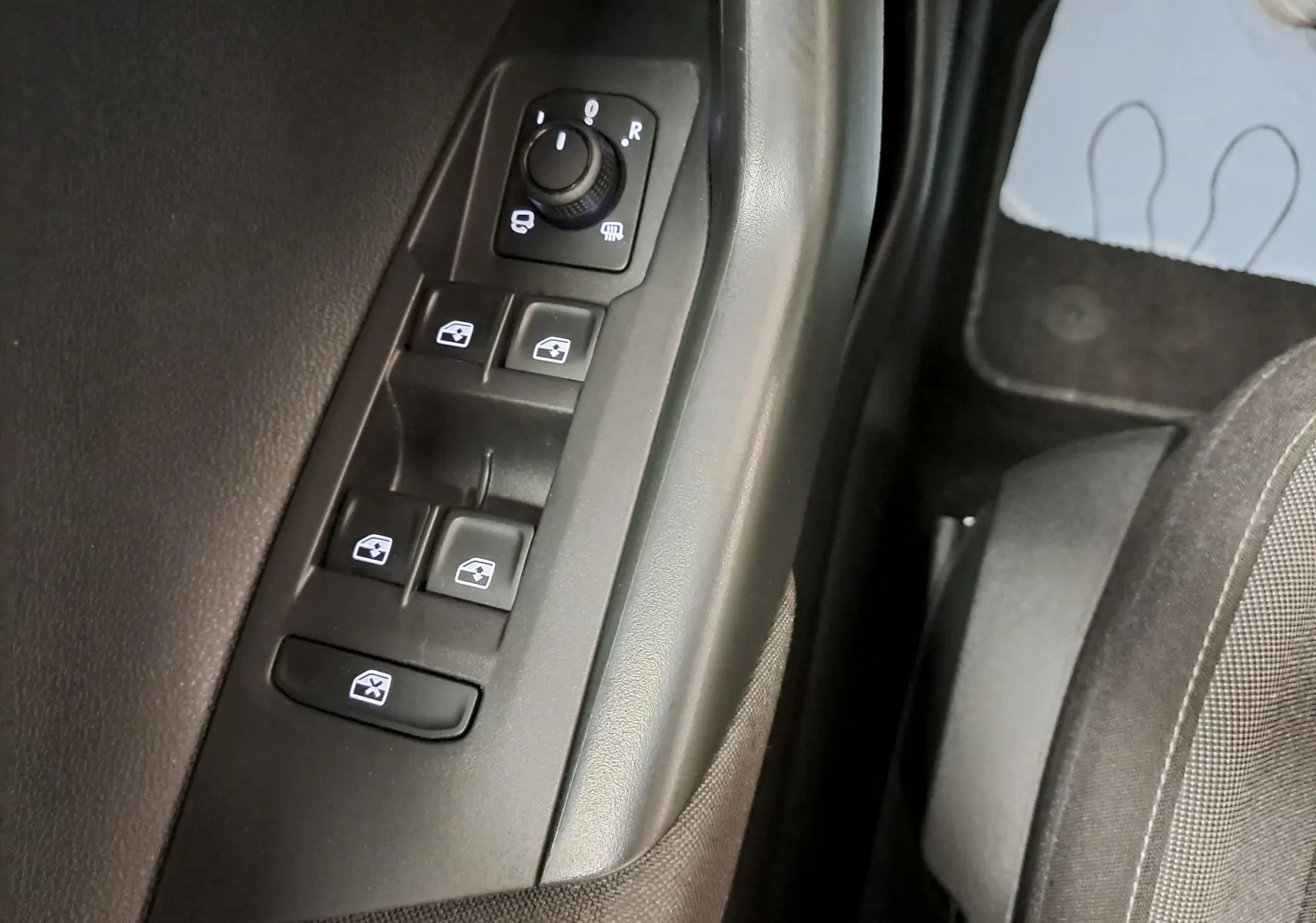 Gros plan sur les commandes de lève-vitres et rétroviseurs côté gauche du Volkswagen Taigo 2025 en intérieur noir.