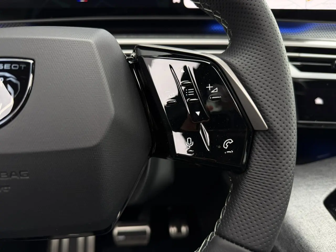 Gros plan sur les commandes à droite du volant perforé du Peugeot 3008 Hybrid GT, intérieur noir élégant.