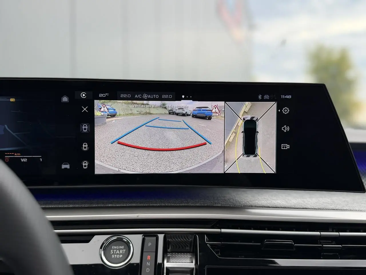 Vue intérieure du tableau de bord du Peugeot 3008 Hybrid 145 GT, écran affichant la caméra de recul et vision 360° en mode stationnement.