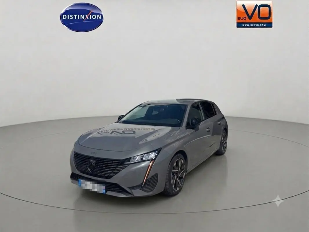 PEUGEOT 308 Hybrid gris vue 3/4 avant droit dans un studio, avec jantes alliage et phares LED allumés.