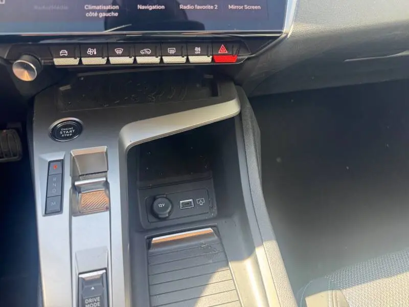 Détail de la console centrale grise de la Peugeot 308 Hybrid 145 e-DCS6 Allure avec levier de vitesses et boutons de commande.