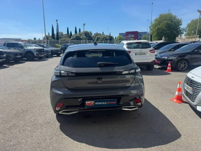Vue arrière d'une Peugeot 308 Hybrid 145 gris métallisé, avec feux LED et double sortie d'échappement visible.