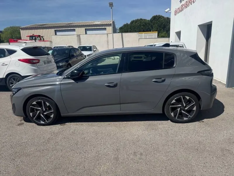 Peugeot 308 Hybrid gris vue de profil côté gauche, avec jantes alliage noires et détails modernes.