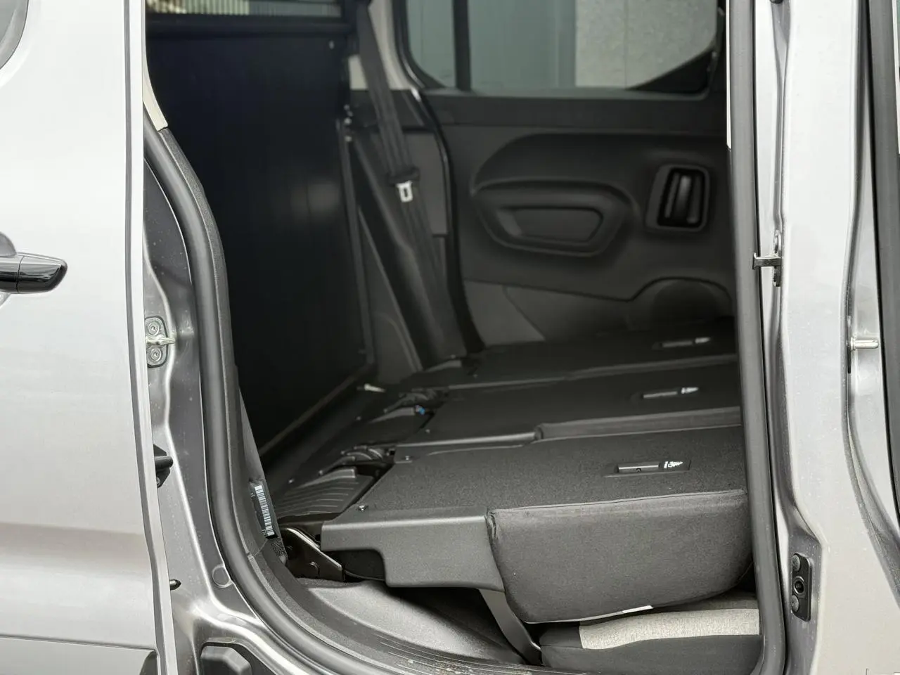 Vue intérieure côté droit du Citroën Berlingo Multispace gris acier avec sièges arrière escamotés et porte coulissante ouverte.
