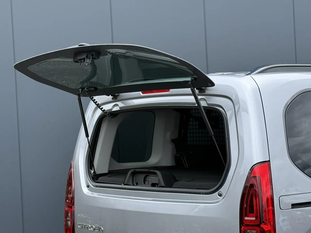 Vue arrière du Citroën Berlingo Multispace gris acier avec lunette arrière ouvrante relevée, dévoilant l'intérieur du coffre.