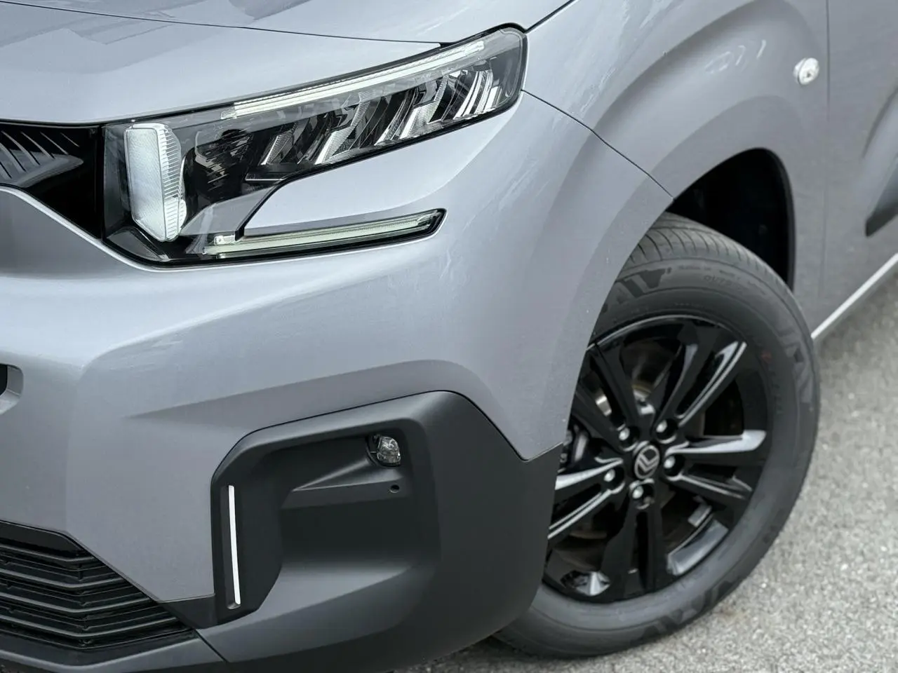 Gros plan sur l'avant droit du Citroën Berlingo Multispace gris acier, avec projecteur LED et jante alliage noire.