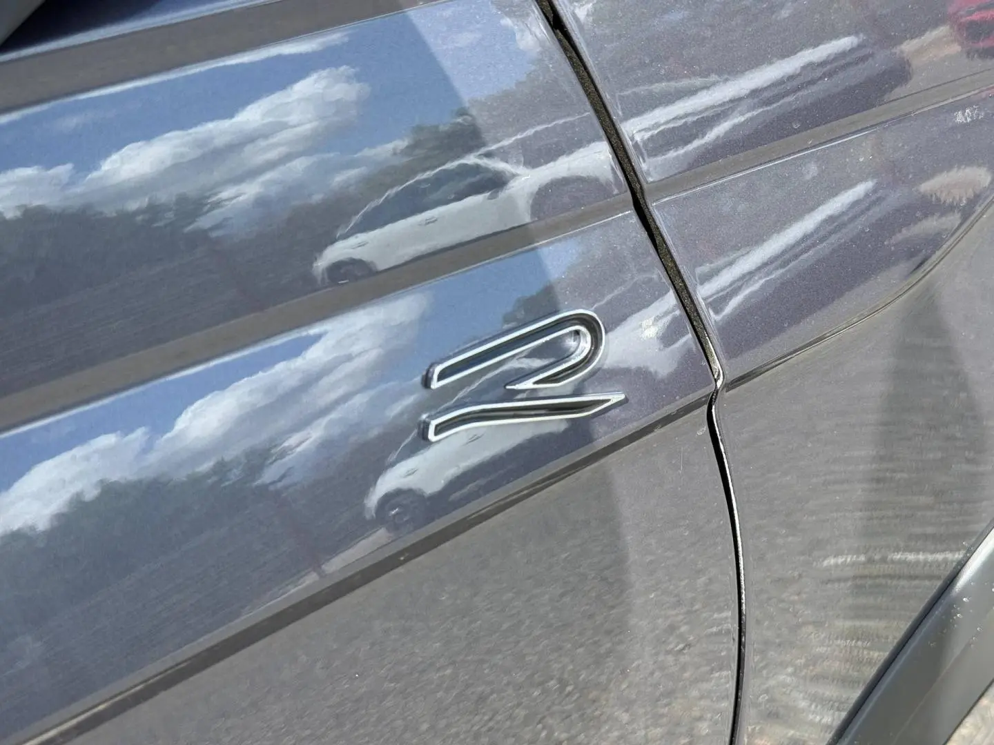 Détail du logo R-Line sur la porte côté gauche d’un Volkswagen Taigo gris Ascot 2025.