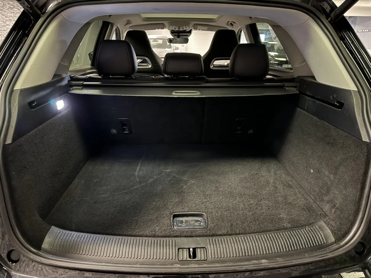 Coffre ouvert vu de l'arrière d'un MG MOTOR EHS noir avec banquette arrière et cache-bagages visibles.