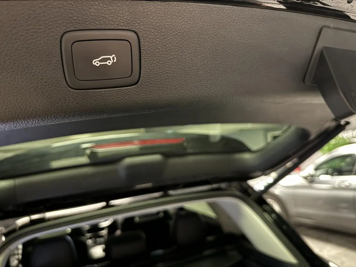 Bouton d'ouverture électrique du hayon sur le bord intérieur du coffre d'un MG MOTOR EHS noir vu de l'arrière ouvert.