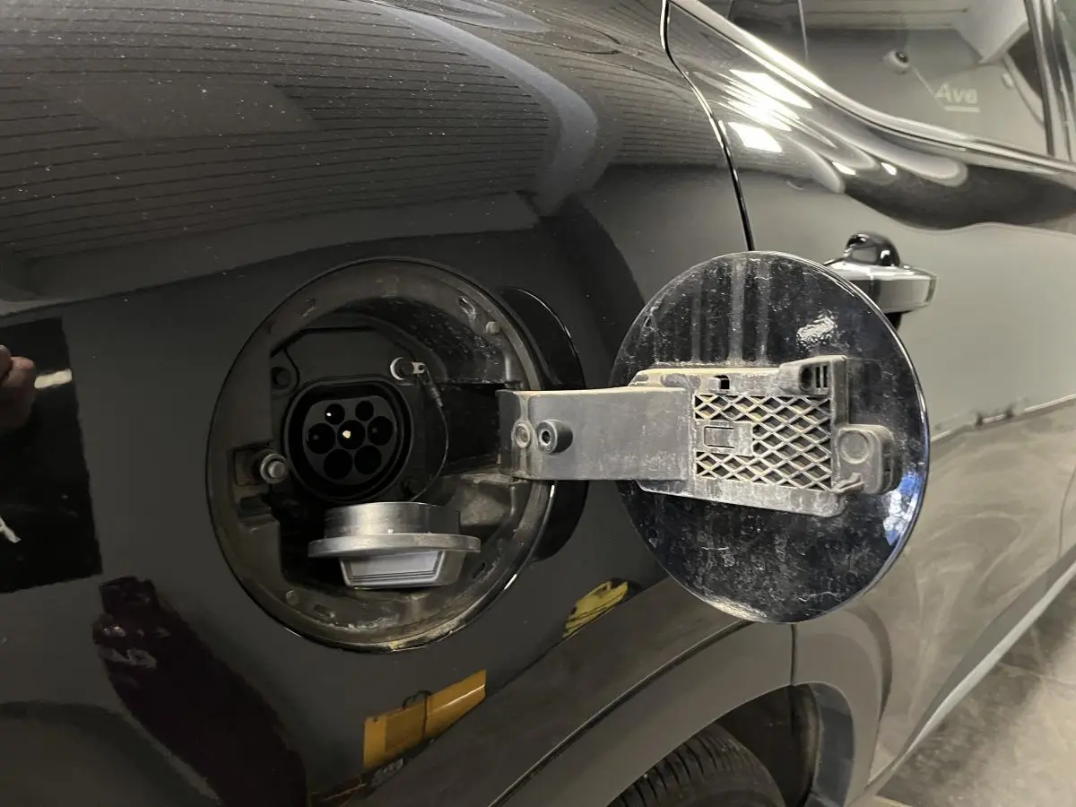 Prise de recharge hybride ouverte côté gauche sur MG MOTOR EHS noire, détail de la trappe et connecteur électrique.