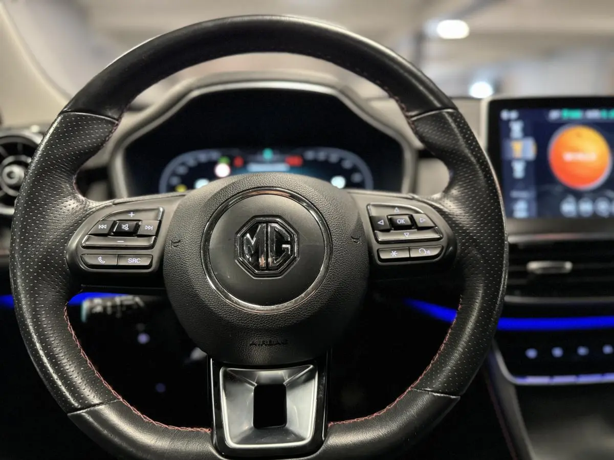 Volant cuir noir perforé avec logo MG au centre, tableau de bord numérique et écran tactile lumineux en arrière-plan